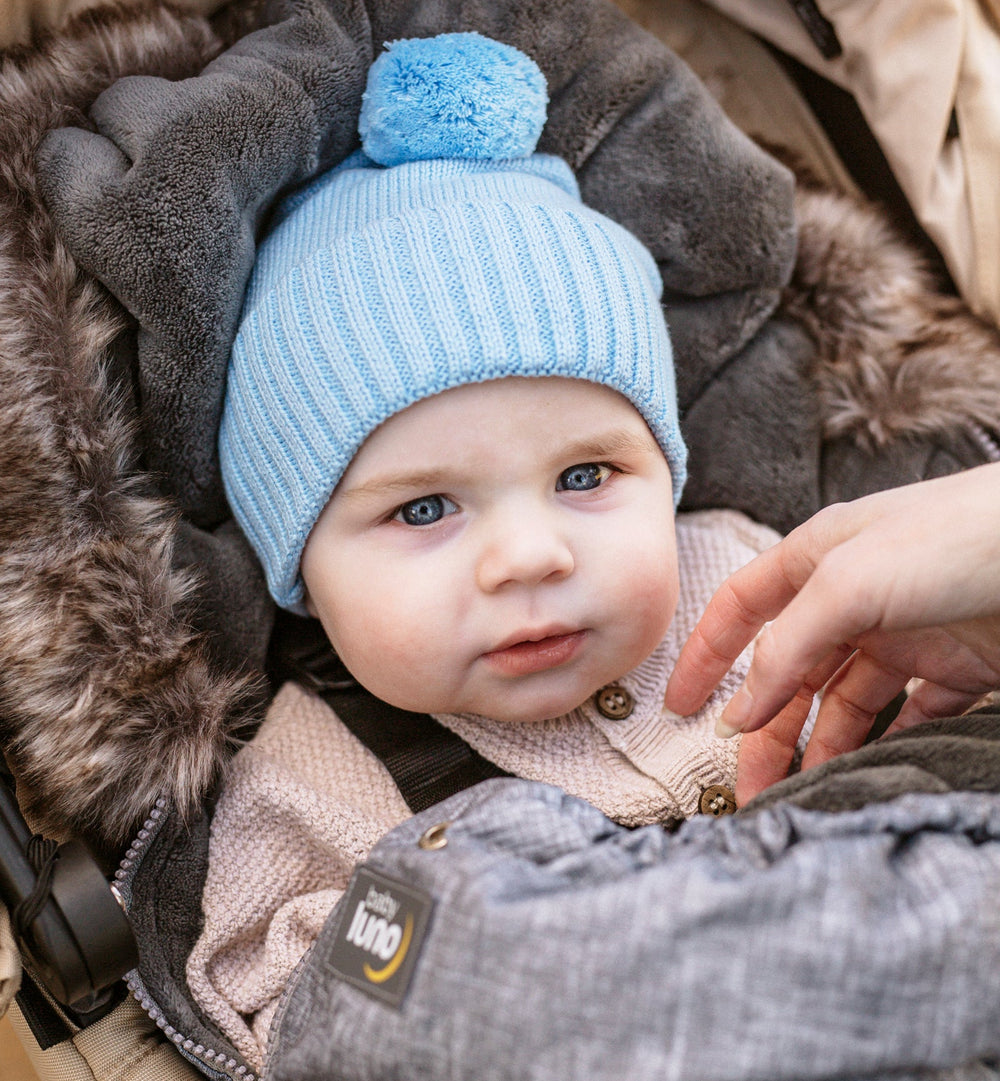 Blue knit beanie with a pom-pom on a white background