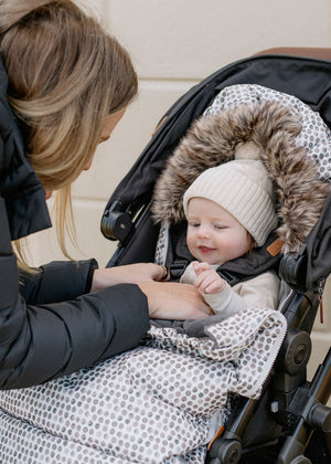 Baby in Raindrops baby luno footmuff stroller liner wearing ivory beanie