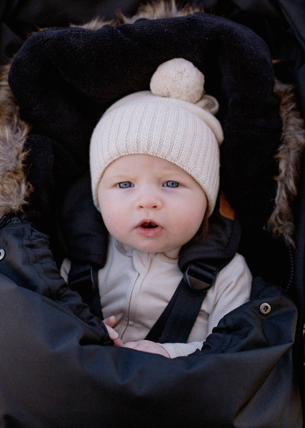 Beige knit beanie with a pom-pom on a white background