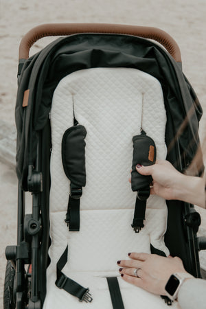 Mother adjusting the baby luno Lite Summer Footmuff cover on a stroller or pram pulling 5 point harness through