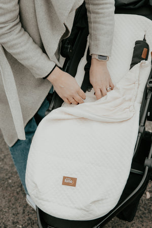 Mother adjusting the baby luno Lite Summer Footmuff cover on a stroller or pram