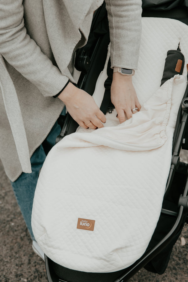 Mother adjusting the baby luno Lite Summer Footmuff cover on a stroller or pram