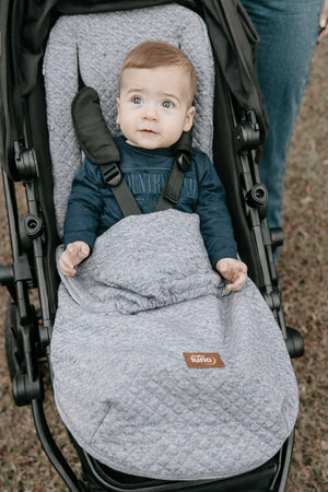 Baby in a stroller with a grey footmuff, brand baby luno